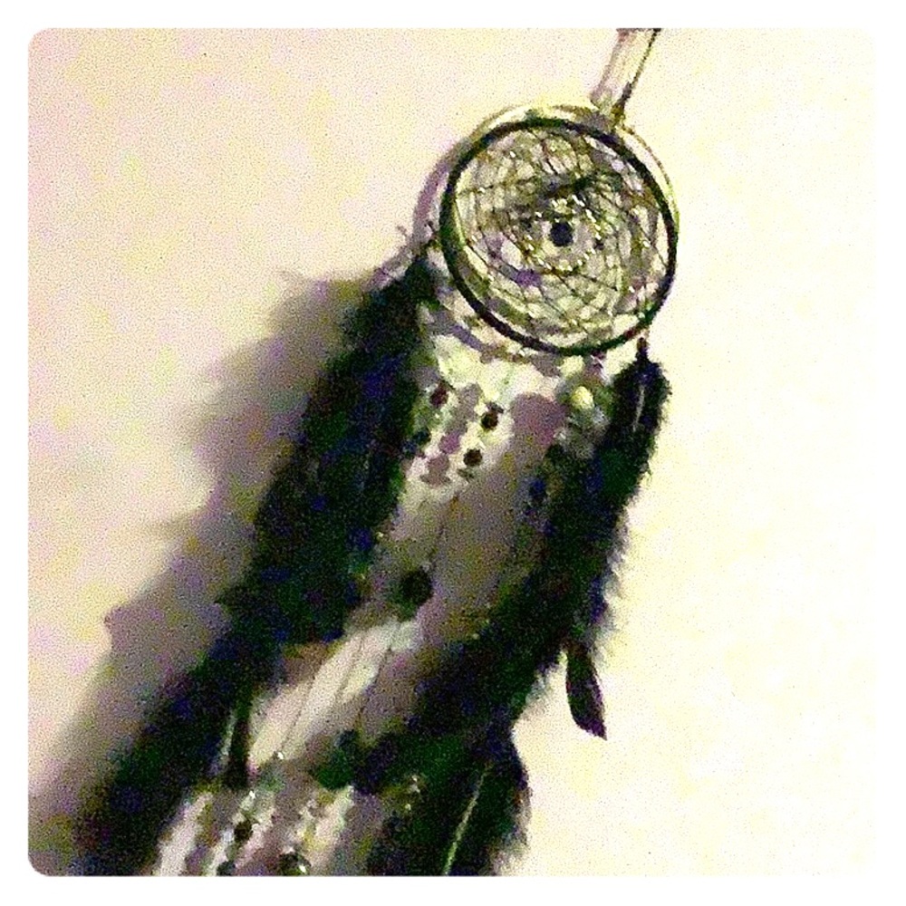 A black dream catcher with beads and feathers